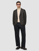 Eine Person, die einen Timeless Wool Blazer Slim in dunkelbraunem Karomuster, einen beigen Rollkragenpullover, eine schwarze Hose und Loafer trägt.
