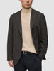 Eine Person, die einen dunkelbraunen, karierten Timeless Wool Blazer Slim über einem beigen Rollkragenpullover und einer schwarzen Hose trägt.