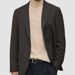 Eine Person, die einen dunkelbraunen, karierten Timeless Wool Blazer Slim über einem beigen Rollkragenpullover und einer schwarzen Hose trägt.