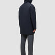 Rückansicht einer Person, die eine schwarze Utility-Jacke aus recyceltem Polyester trägt, kombiniert mit einer grauen Hose und schwarzen Schuhen.