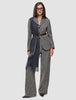 Eine Person trägt einen grauen Blazer aus Bouclé mit Fischgrätenmuster und dazu passende Women Ashryn Pants Wide Domino Herringbone, die mit einem dunkelbraunen Gürtel tailliert und durch einen langen, anthrazitfarbenen Schal mit Fransen akzentuiert werden.