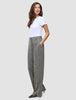 Eine Frau, die ein weißes T-Shirt und die Women Ashryn Pants Wide Domino Herringbone trägt, eine graue, gemusterte Bouclé-Hose mit weitem Bein und Vordertaschen.