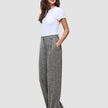 Eine Frau, die ein weißes T-Shirt und die Women Ashryn Pants Wide Domino Herringbone trägt, eine graue, gemusterte Bouclé-Hose mit weitem Bein und Vordertaschen.