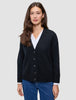 Eine Frau trägt eine schwarze, grob gestrickte, weiche Wollstrickjacke für Damen über einem weißen Hemd und einer blauen Jeans.