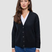 Eine Frau trägt eine schwarze, grob gestrickte, weiche Wollstrickjacke für Damen über einem weißen Hemd und einer blauen Jeans.