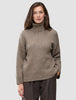Frau, die einen grob gestrickten, weichen Wollpullover mit Rollkragen in der Farbe Taupe Melange trägt.