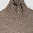 Damen-Rollkragenpullover aus grobem, weichem Wollstrick in Taupe-Melange mit gerippter Struktur.