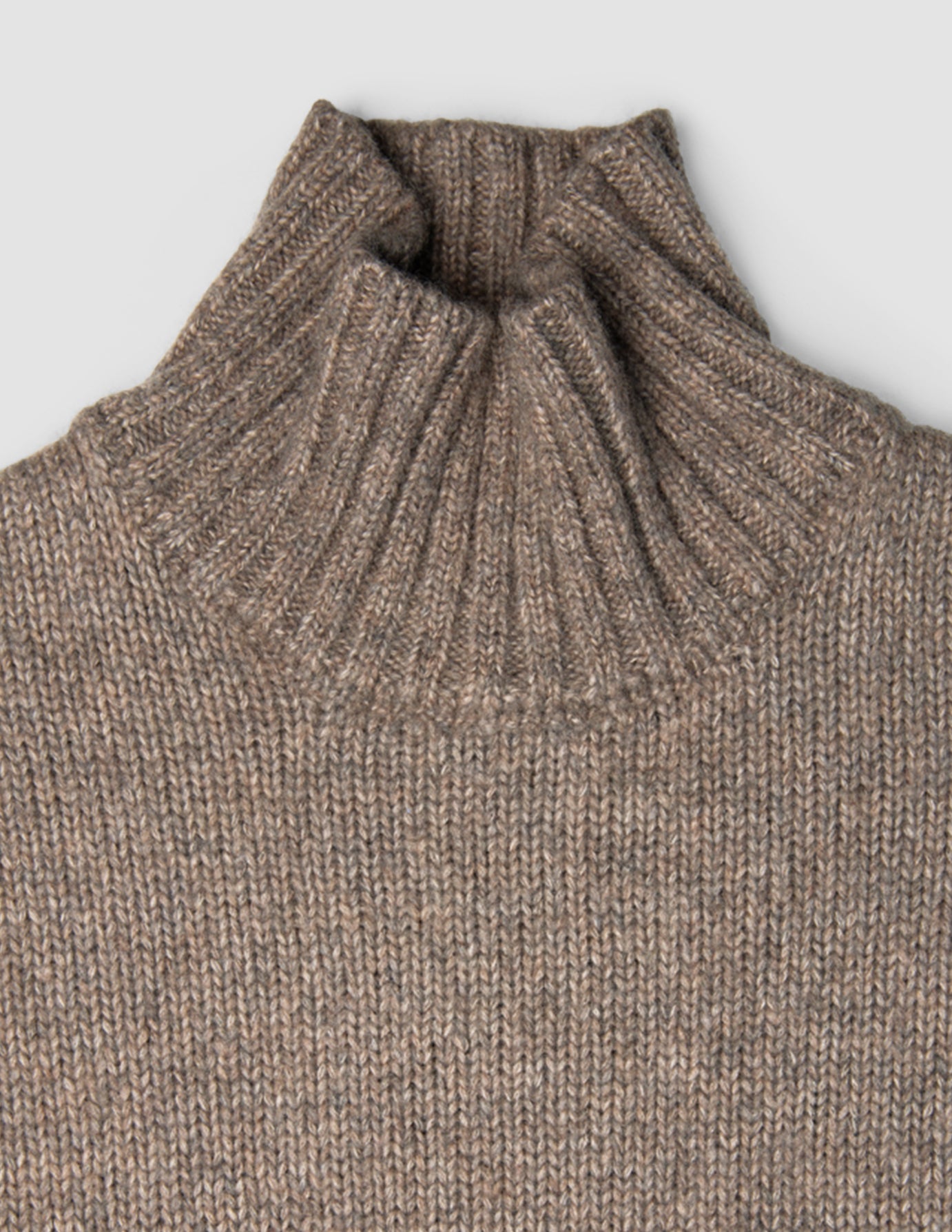 Damen-Rollkragenpullover aus grobem, weichem Wollstrick in Taupe-Melange mit gerippter Struktur.
