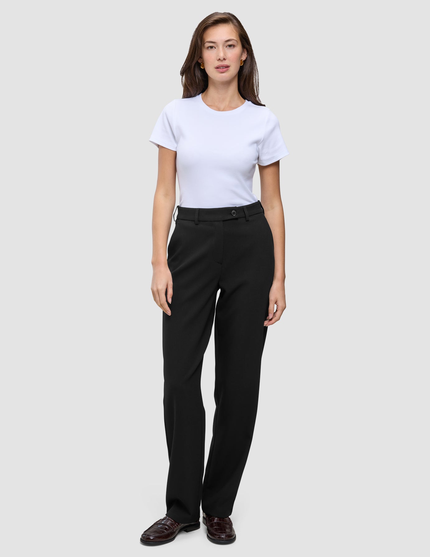 Eine Frau, die ein weißes T-Shirt und eine Women GO2 Pants Straight Black mit geradem Bein trägt.