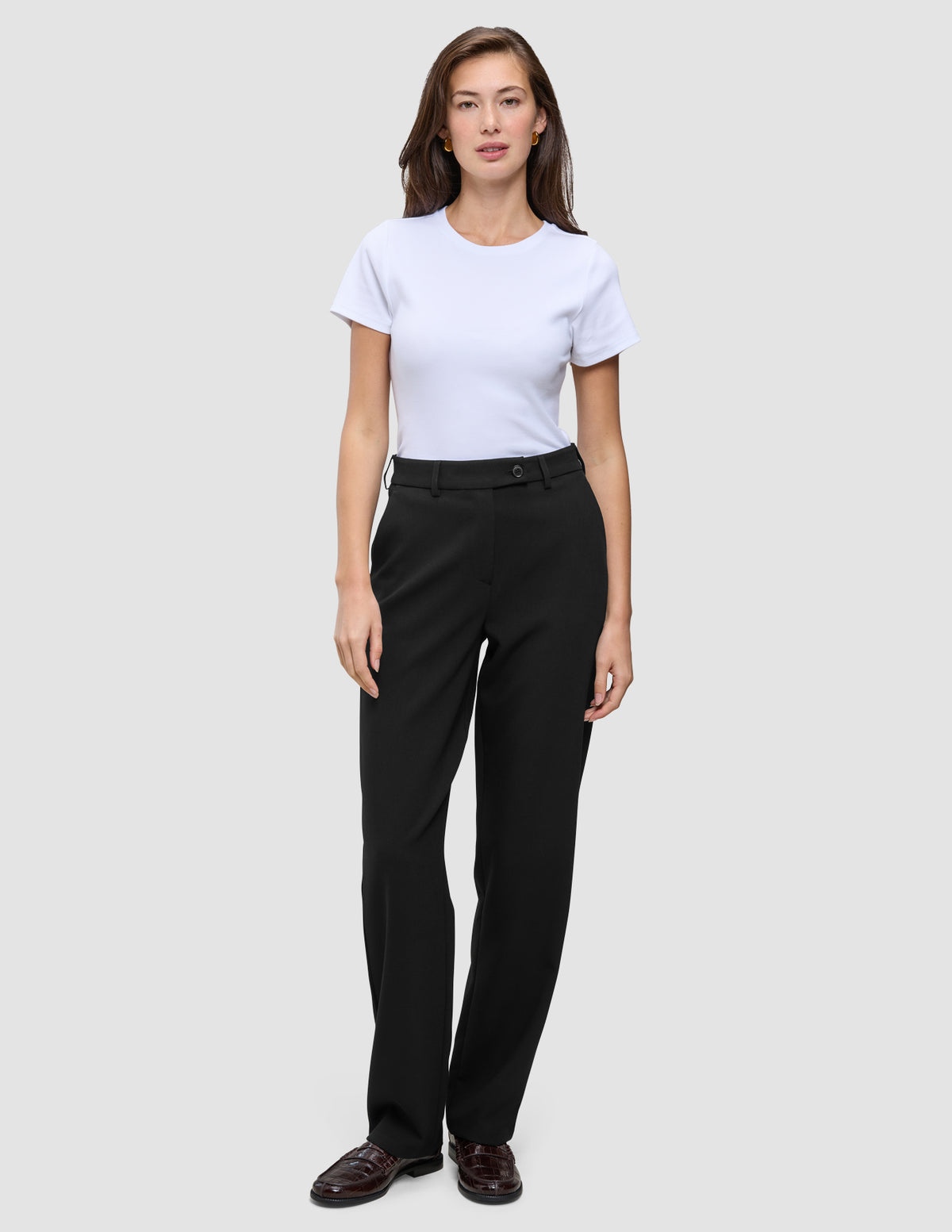 Eine Frau, die ein weißes T-Shirt und eine Women GO2 Pants Straight Black mit geradem Bein trägt.