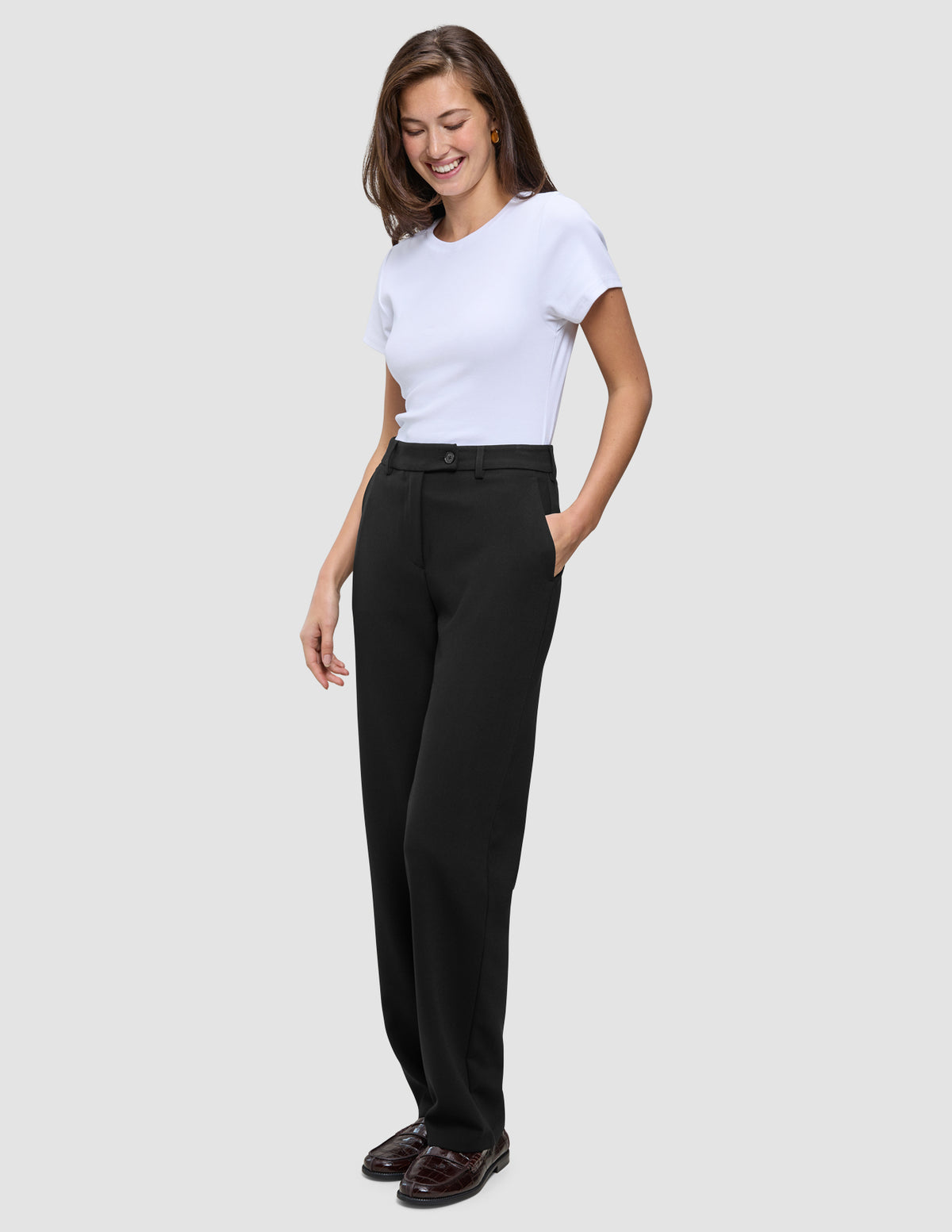Eine Frau, die ein weißes T-Shirt und eine Women GO2 Pants Straight Black in einem schlichten, skandinavischen Design trägt.