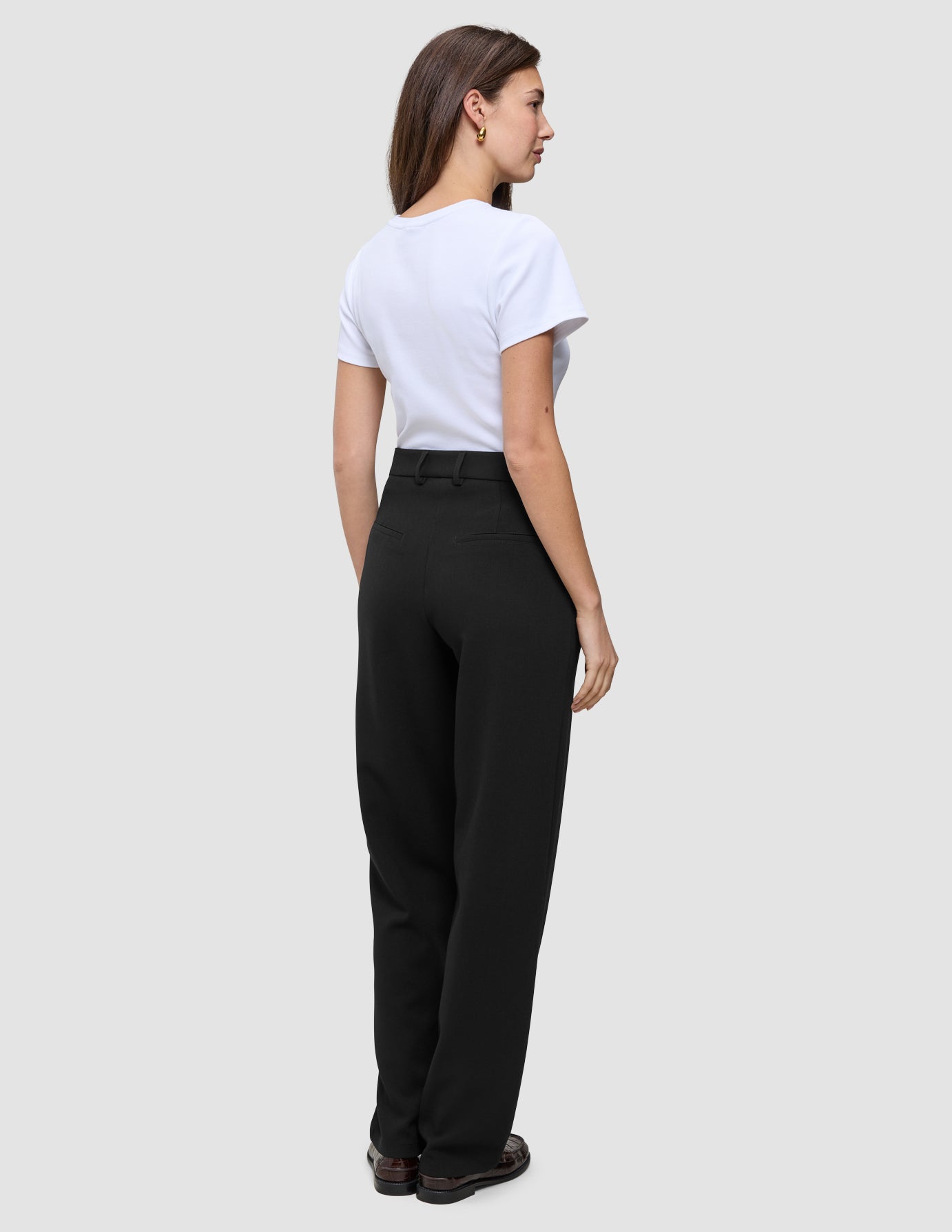Eine Frau, von hinten gesehen, die ein weißes T-Shirt und eine Women GO2 Pants Straight Black mit hoher Taille und geradem Bein trägt.