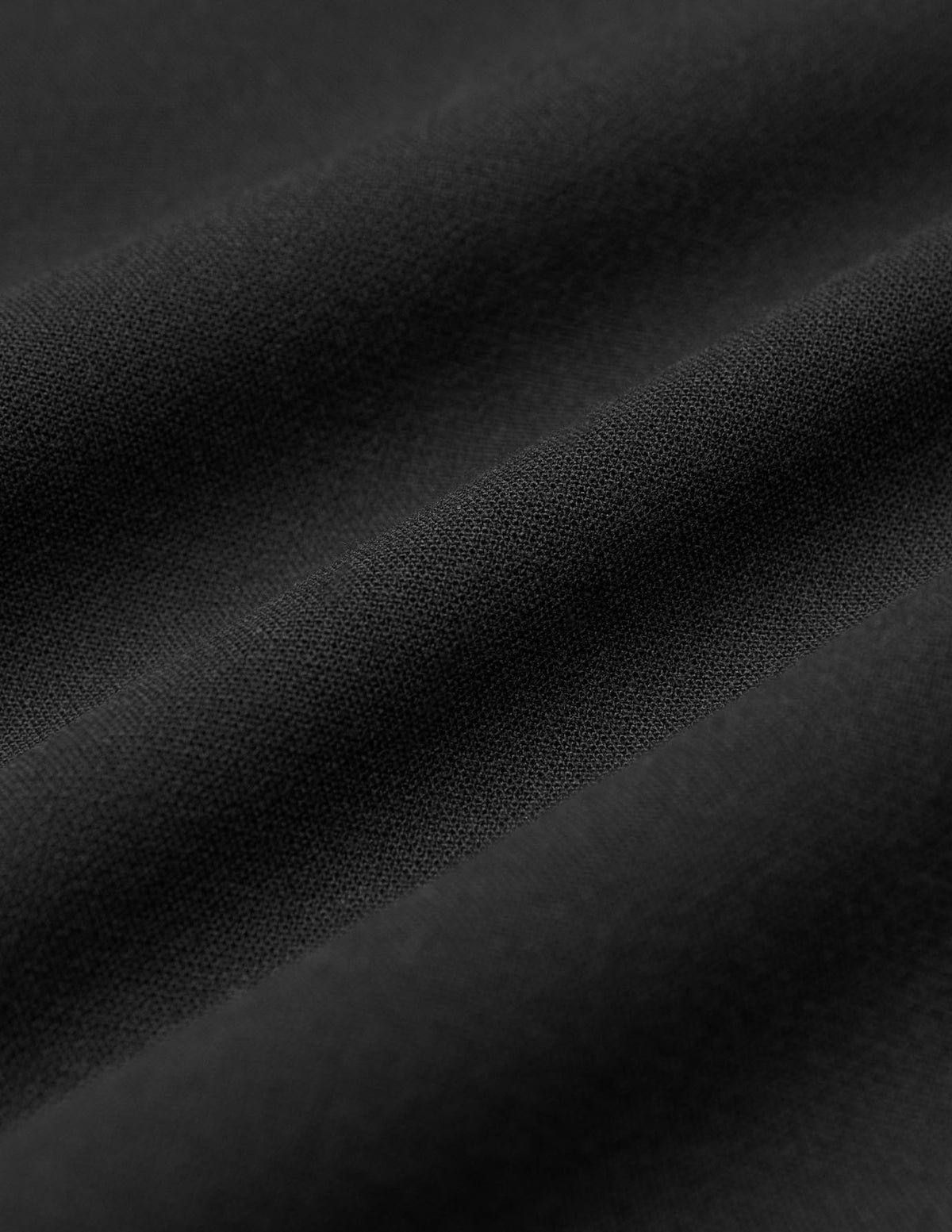 Nahaufnahme der Falten im schwarzen Stoff der Women GO2 Pants Straight Black mit feiner Double-Face-Webart.