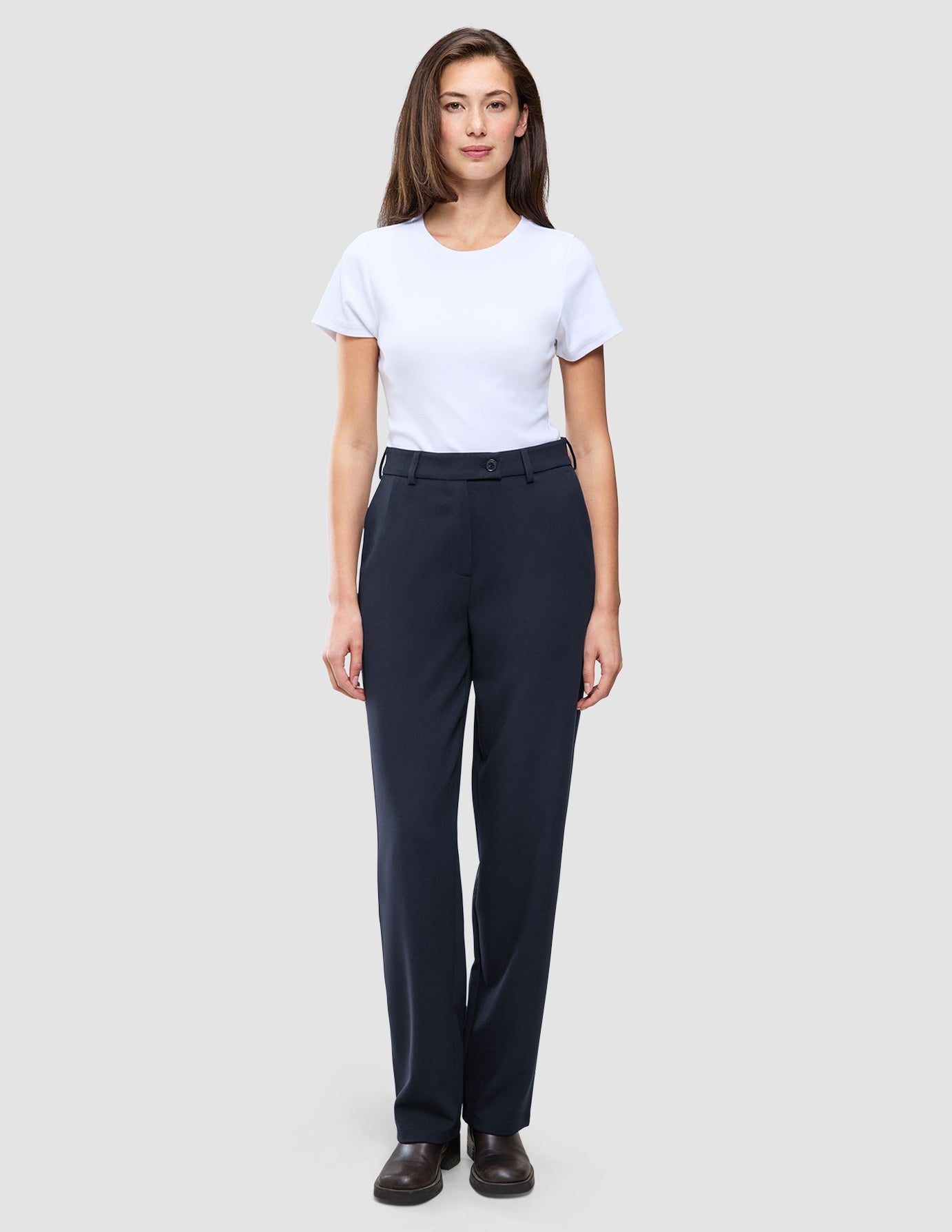 Eine Frau in einem weißen T-Shirt und einer Women GO2 Pants Straight Blue Nights in Dunkelblau mit geradem Schnitt, die das minimalistische skandinavische Design widerspiegelt.