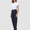 Eine Frau in einem weißen T-Shirt und einer Women GO2-Hose Straight Blue Nights mit geradem Bein, die ein klares, skandinavisches Design widerspiegelt.