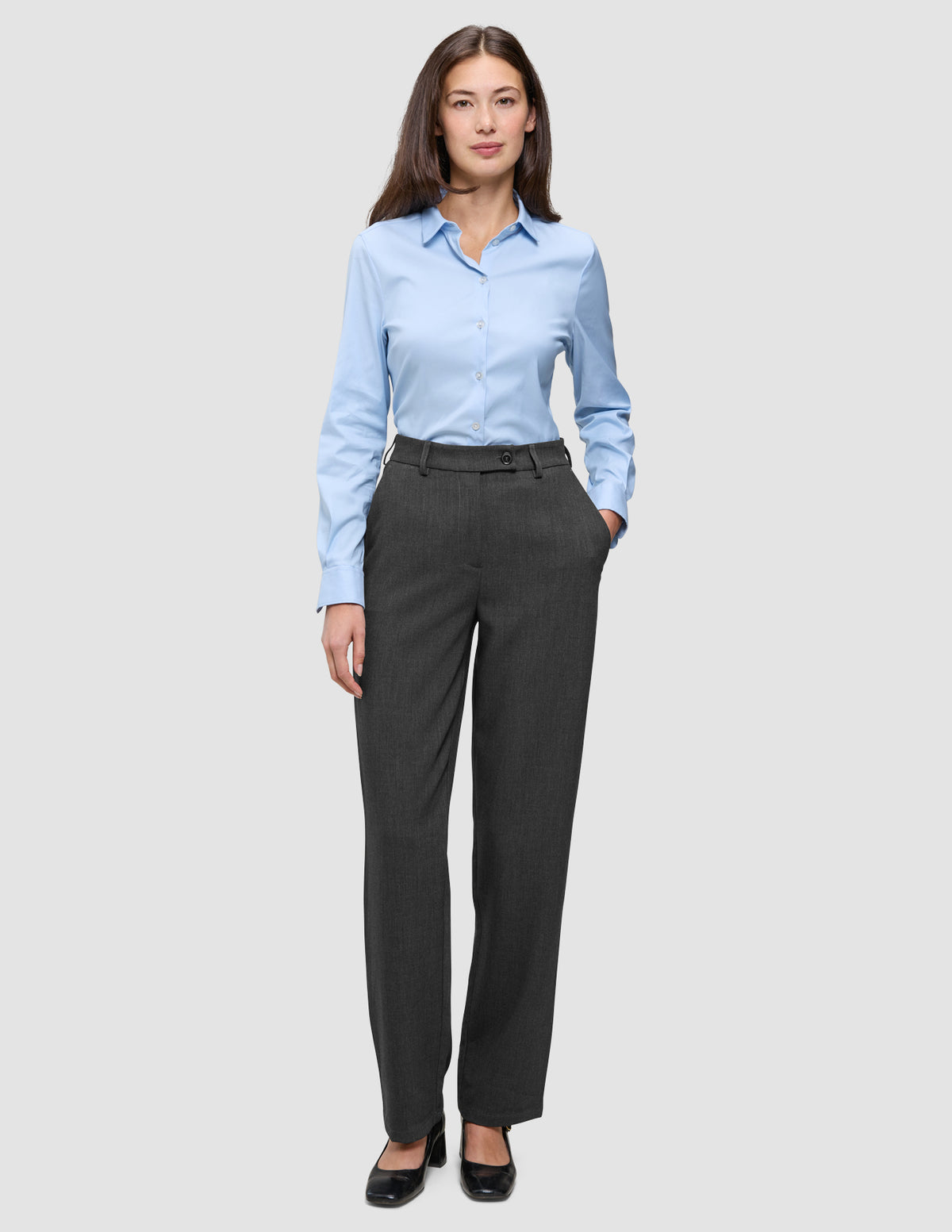 Eine Frau, die ein hellblaues Hemd mit Knöpfen und eine Women GO2 Pants Straight in Dunkelgrau-Melange trägt, die sich durch ein schlichtes, skandinavisches Design auszeichnet.