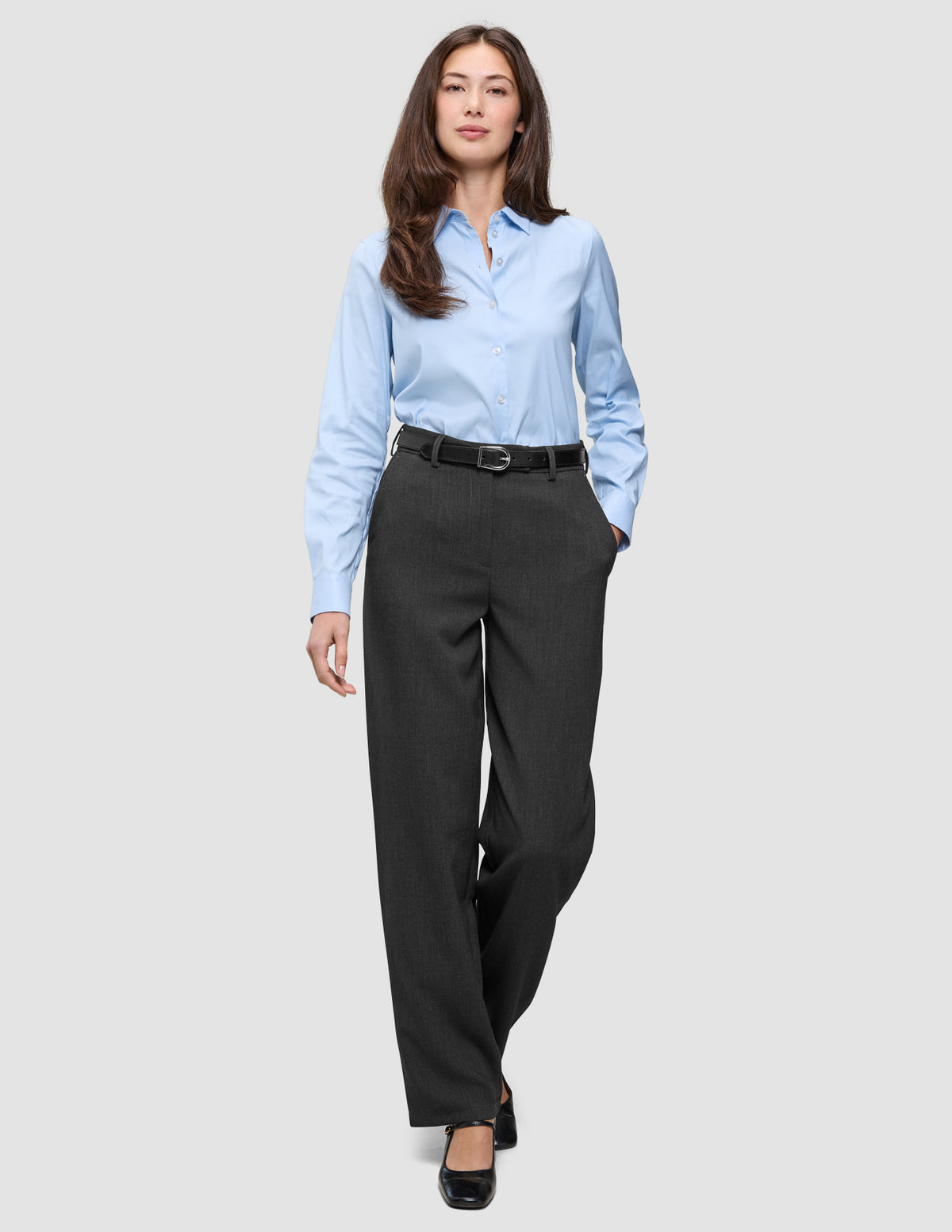 Eine Frau in einem hellblauen Hemd mit Knöpfen und einem schwarzen Gürtel trägt die Women GO2 Pants Straight Dark Grey Melange und präsentiert damit einen minimalistischen Look, der vom skandinavischen Design inspiriert ist.