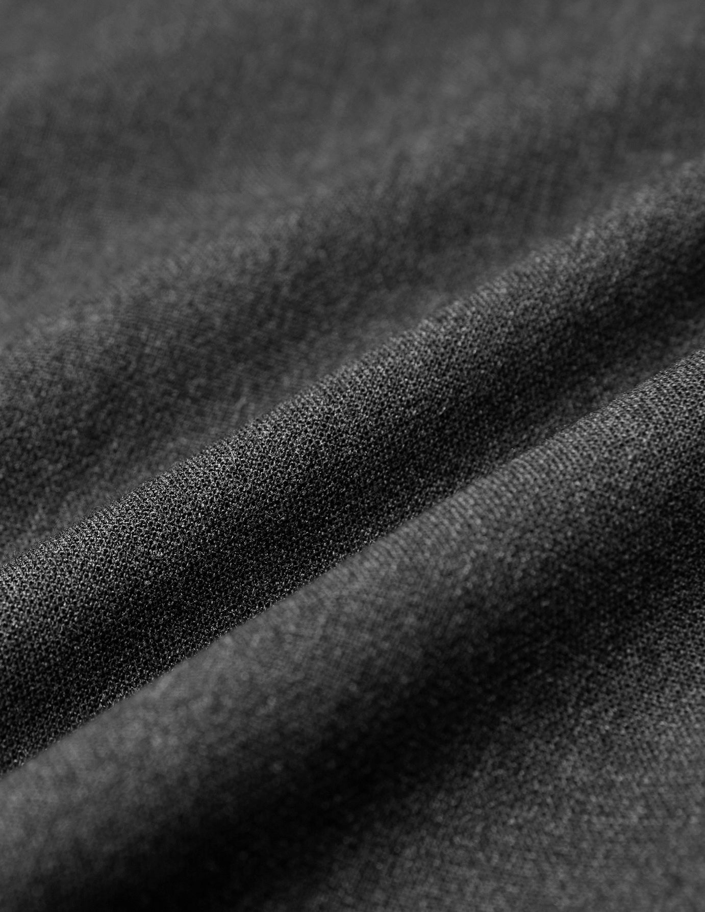 Nahaufnahme der Women GO2 Pants Straight Dark Grey Melange aus dunkelgrauem Doubleface-Material mit sichtbarer Webstruktur, hier in weichen Falten dargestellt.