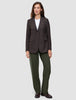 Eine Person trägt einen braunen Blazer mit Nadelstreifen über einem weißen T-Shirt, dazu die Hose Women GO2 Pants Straight Dusty Olive und dunkle Loafer – ein eleganter Look ganz im Sinne des skandinavischen Designs.