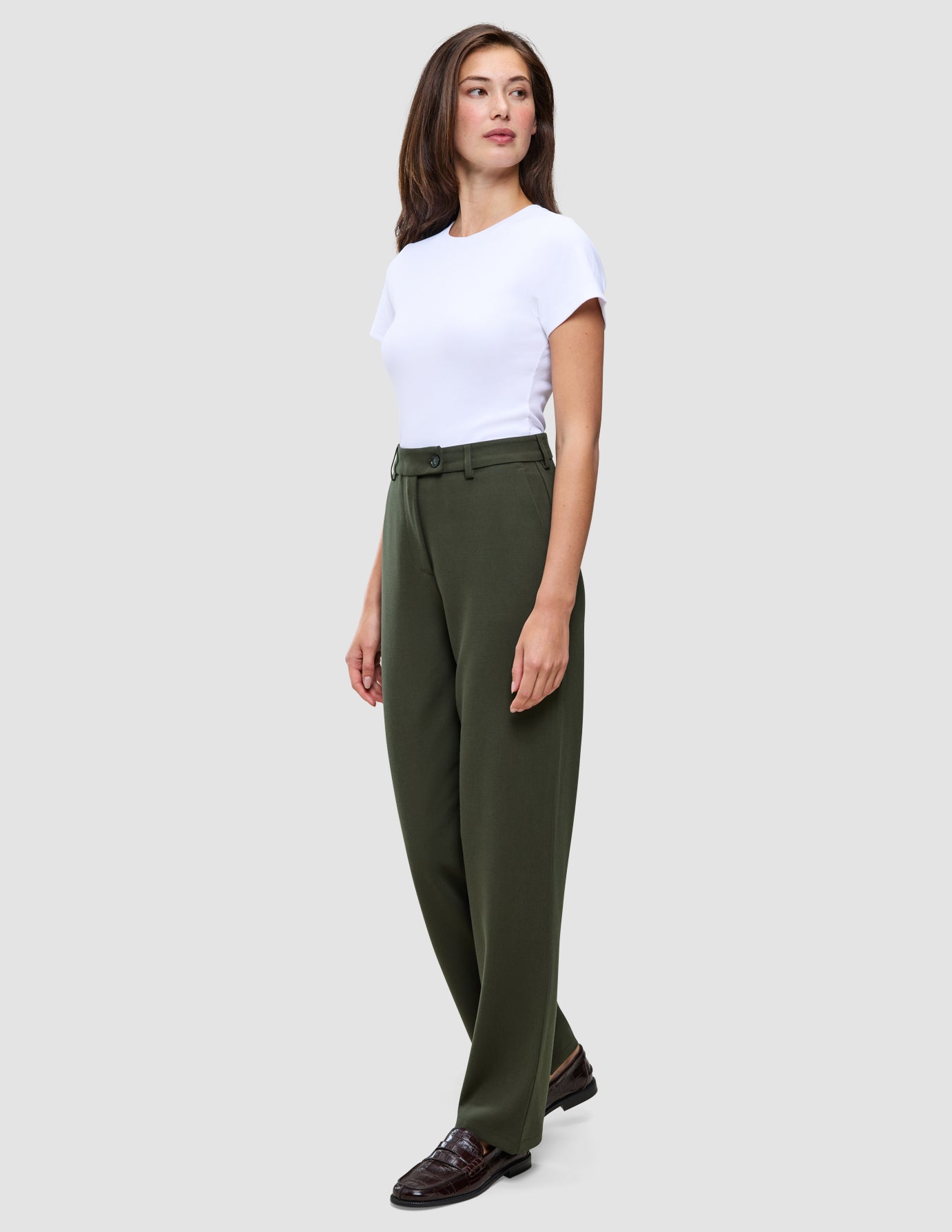 Eine Frau in einem weißen T-Shirt und einer Women GO2 Pants Straight Dusty Olive mit geradem Schnitt, im Profil stehend.