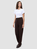 Eine Frau, die ein weißes T-Shirt, eine Women GO2 Pants Straight Mocha und dunkle Loafer trägt, die ein klares, skandinavisches Design widerspiegeln.