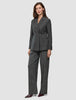 Eine Frau trägt einen Women Nara Blazer Fitted Black Check in Anthrazitgrau sowie eine dazu passende Hose mit weitem Bein und dezentem Karomuster, die ein elegantes, skandinavisch inspiriertes Design präsentieren.