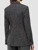 Eine Person, von hinten gesehen, die einen Women Nara Blazer Fitted Black Check trägt – ein taillierter Blazer mit schwarz-weißem Mikrokaromuster und 360°-Stretch.