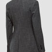 Eine Person, von hinten gesehen, die einen Women Nara Blazer Fitted Black Check trägt – ein taillierter Blazer mit schwarz-weißem Mikrokaromuster und 360°-Stretch.