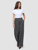 Eine Frau trägt ein weißes T-Shirt und die Hose Women Nara Pants Wide Black Check mit hoher Taille und dezentem Karomuster.