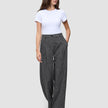 Eine Frau trägt ein weißes T-Shirt und die Hose Women Nara Pants Wide Black Check mit hoher Taille und dezentem Karomuster.