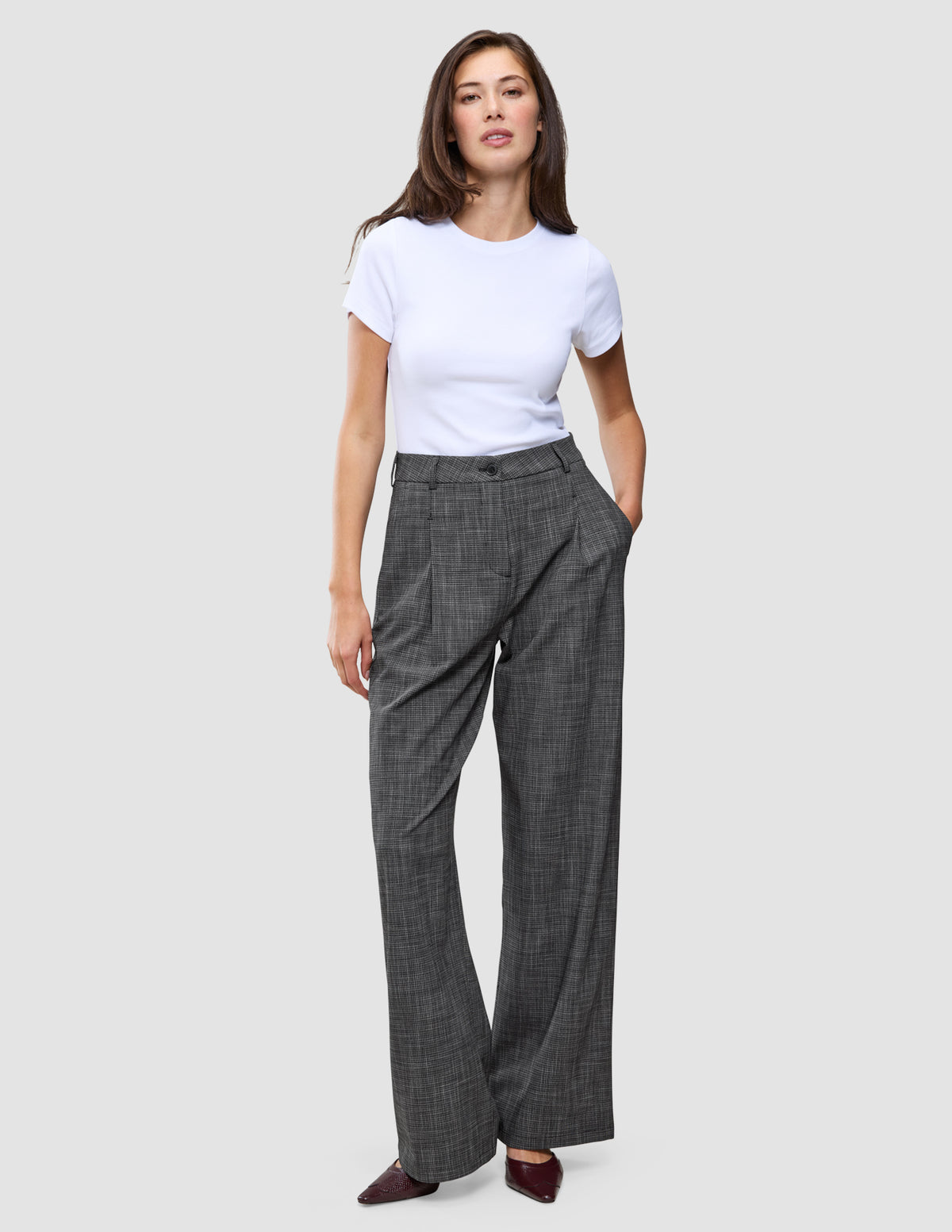 Eine Frau trägt ein weißes T-Shirt und eine hoch taillierte Damenhose Nara Pants Wide Black Check.