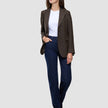 Eine Frau, die einen Women Serene Blazer Regular Walnut Herringbone über einem weißen T-Shirt und dunkelblauen Jeans trägt.
