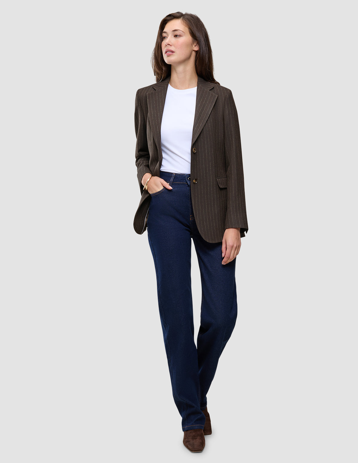 Eine Frau, die einen Women Serene Blazer Regular Walnut Herringbone über einem weißen T-Shirt und dunkelblauen Jeans trägt.