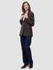 Eine Person trägt den Women Serene Blazer Regular Walnut Herringbone über einem weißen T-Shirt, dunkelblauen Jeans und braunen Stiefeletten.
