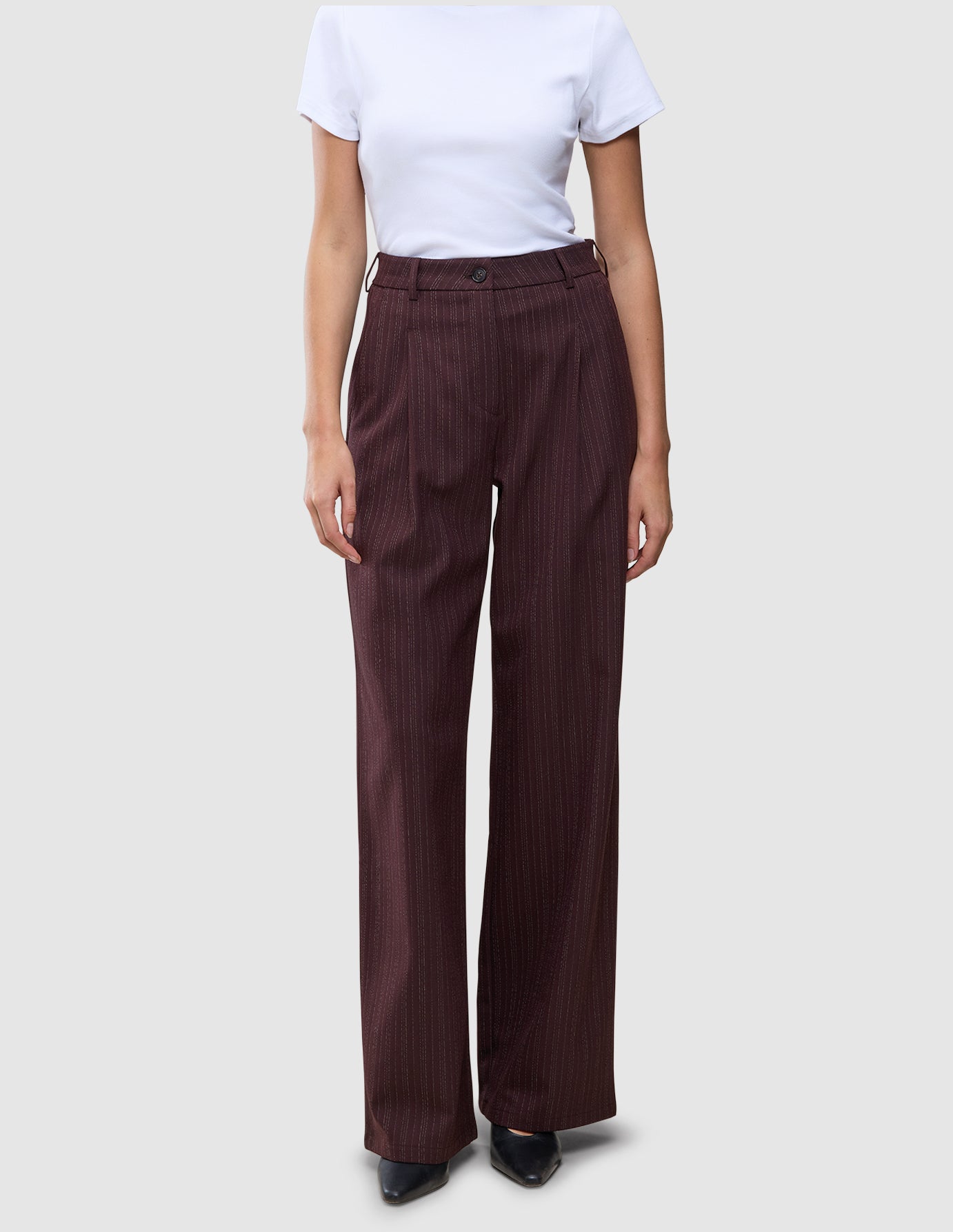 Damenhose Serene Wide Berry Pinstripe in dunklem Beerenrot mit hoher Taille, weitem Bein und vertikalen Nadelstreifen, kombiniert mit einem weißen T-Shirt für einen Hauch von skandinavischem Design.