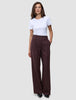 Eine Frau trägt ein weißes T-Shirt und eine burgunderrote, weit geschnittene Hose mit Nadelstreifen – das Modell Women Serene Pants Wide Berry Pinstripe.