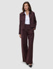 Eine Frau, die einen Anzug der Marke Women Serene Pants Wide Berry Pinstripe mit weitem Hosenbein über einem weißen Hemd trägt.