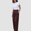 Eine Frau trägt ein weißes T-Shirt und die Women Serene Pants Wide Berry Pinstripe – eine hoch taillierte, weit geschnittene Hose in Beerenfarbe mit Nadelstreifen im skandinavischen Design.