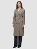 Eine Frau trägt einen Women Wool Coat Greige – einen zweireihigen Wollmantel mit Gürtel – über einem weißen Hemd und einer schwarzen Hose.